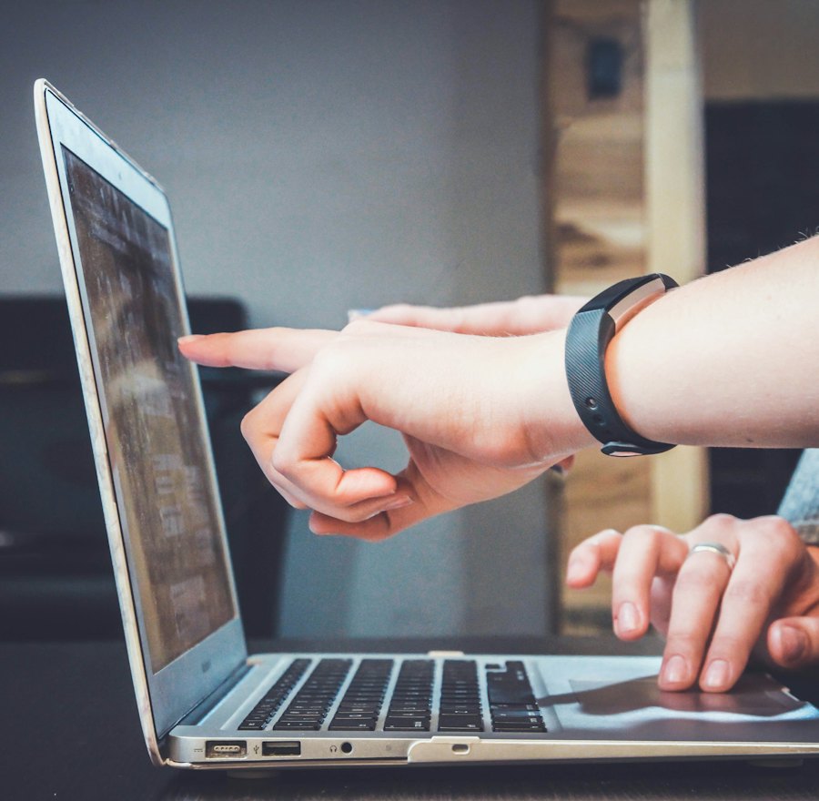 A trainer guiding a student through coding on a laptop